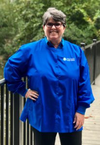 Lynn, smiling, in a bright blue Prime Family Dental scrub top.