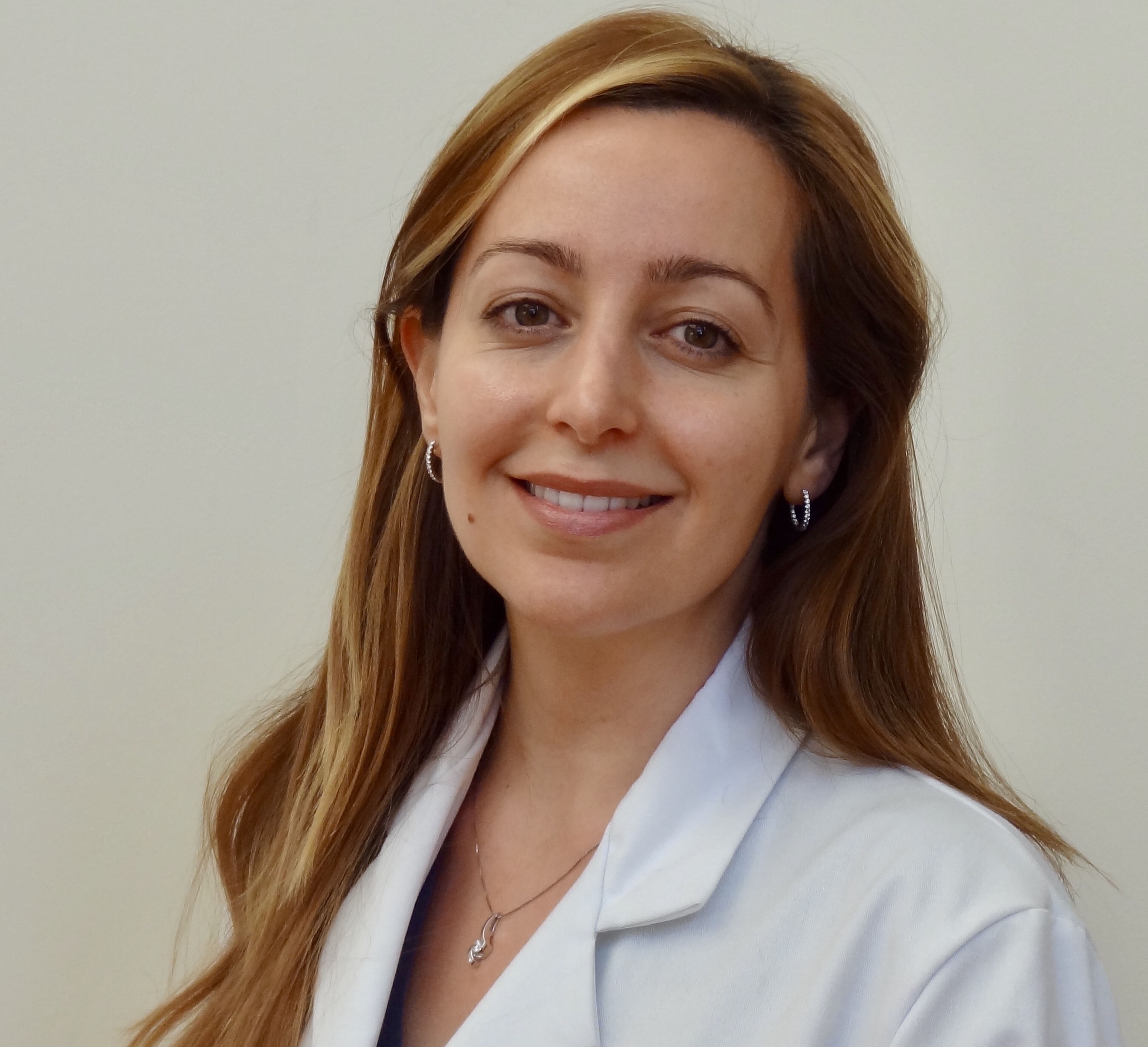 Dr. Verga smiling in a white lab coat.